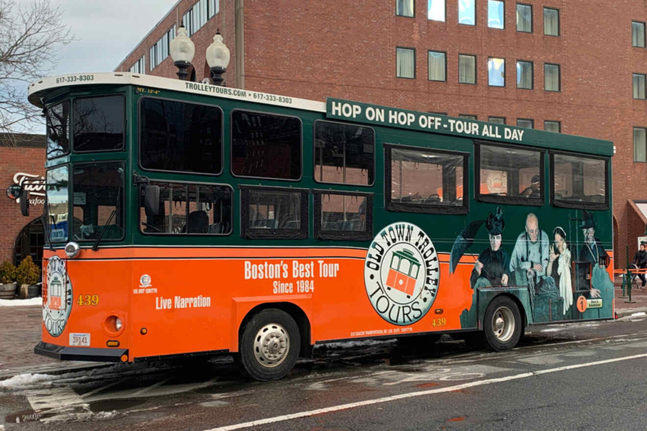 view of a hop-on hop-off trolley in Boston, this time an orange vehicle with historical figures depicted, parked on a city street
