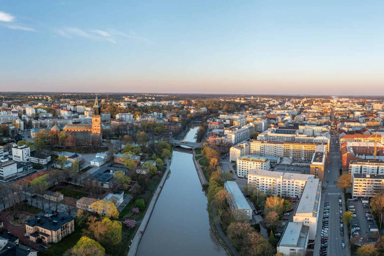 Aerial view of Turku at dusk, showing the dome of the Turku Art Museum amidst a tapestry of autumn-colored trees and urban landscape
