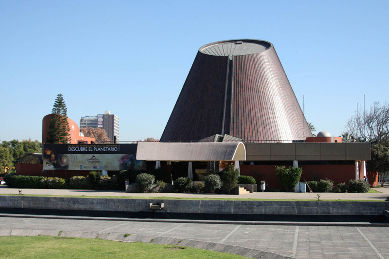 The Planetario de Chile in Santiago, a modern astronomy museum with a distinctive conical roof and an educational banner at the entrance