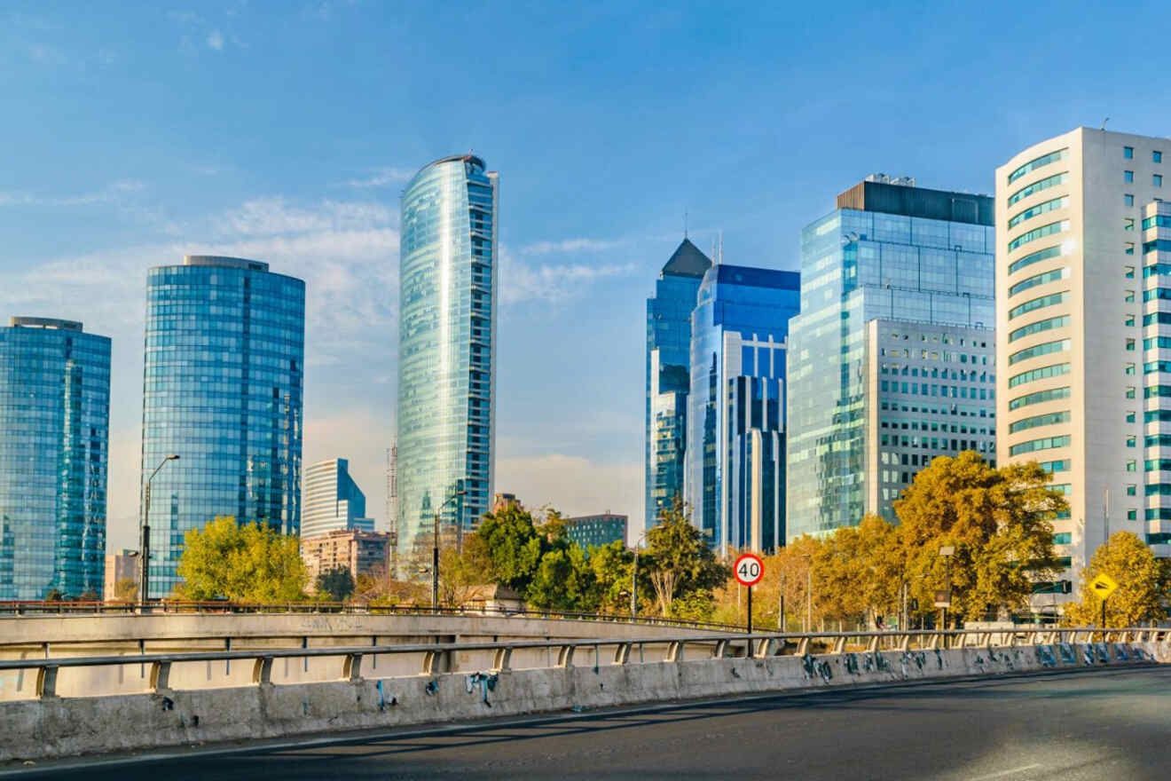 Modern architecture in Santiago, Chile, featuring high-rise buildings along a tree-lined avenue under a blue sky with scattered clouds