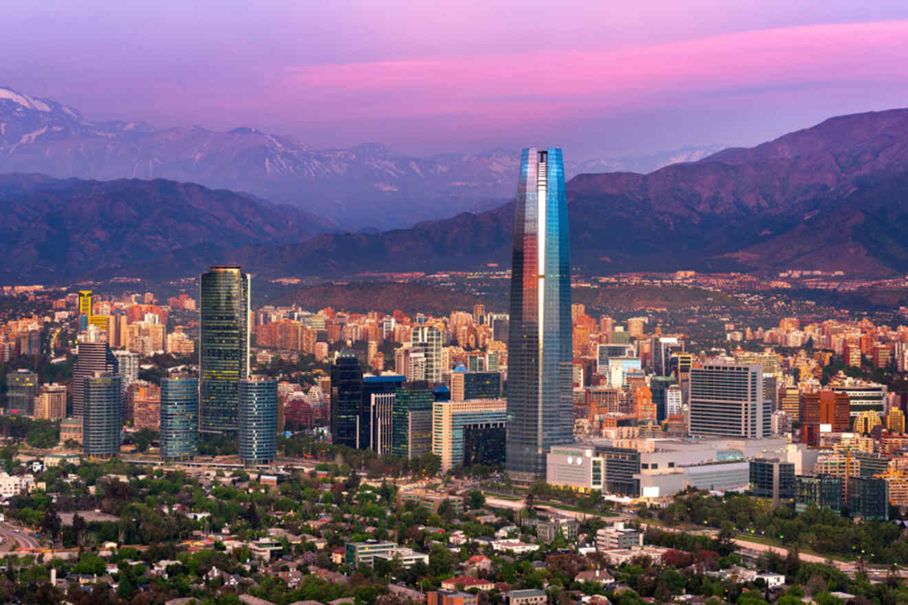 Twilight falls over Santiago, Chile, with the Gran Torre Santiago skyscraper prominently lit against the Andean mountain backdrop