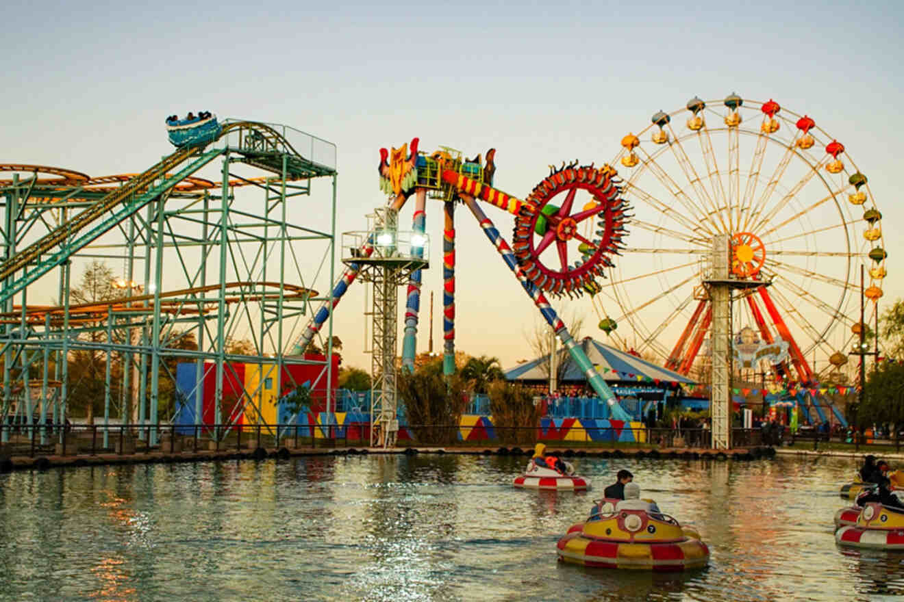 The colorful and lively atmosphere of Parque de la Costa, an amusement park in Buenos Aires, with various rides and attractions alongside a water body as the sun sets