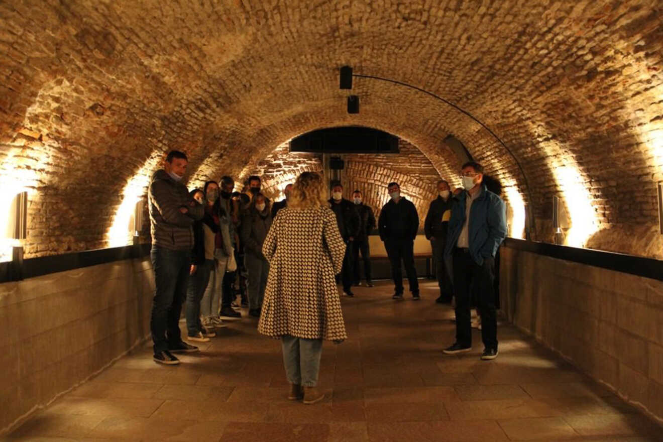 Visitors experiencing the historic El Zanjón de Granados, Buenos Aires, a subterranean architectural wonder, during a guided tour along the brick-lined tunnels
