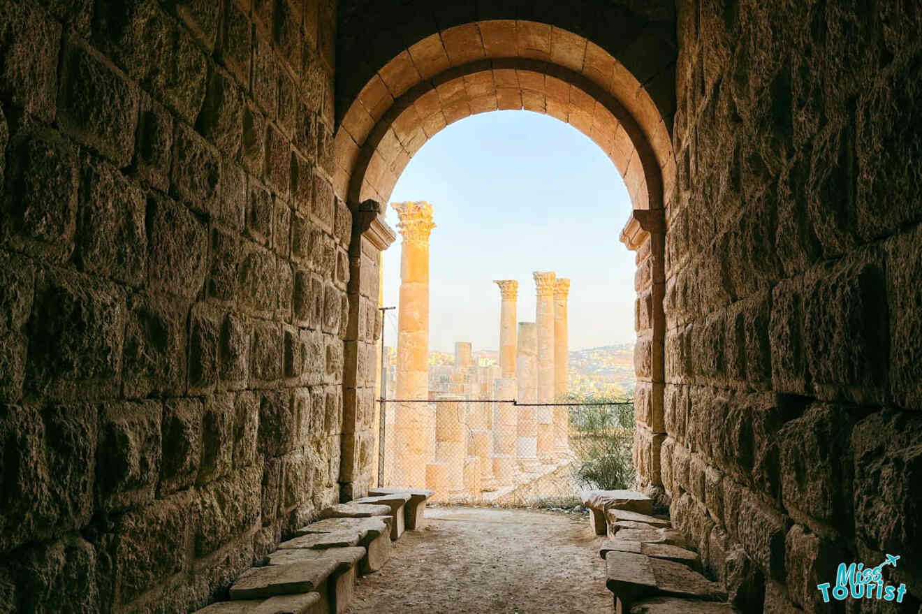 A framed view from the archway of the Amman Citadel, overlooking the towering ancient columns with the cityscape in the distance