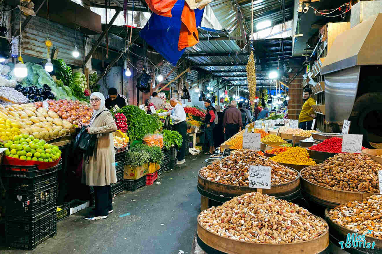 A bustling indoor market in Amman, Jordan, filled with fresh produce and nuts, with shoppers and vendors engaging in the vibrant local commerce