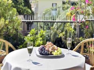 Balcony table set with fruit and wine overlooking a lush garden