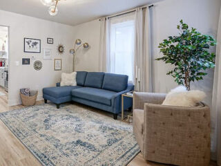 Cozy living room with a blue sectional sofa, beige armchair, decorative rug, and a variety of wall art