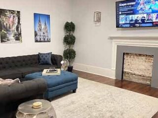 Comfortable and spacious living room in the Broughton Vacation Home with a plush sofa, fireplace, and mounted TV for entertainment.