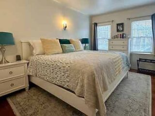 A comfortable bedroom with a queen-sized bed, teal and beige accents, and a patterned rug, creating a serene and inviting space.