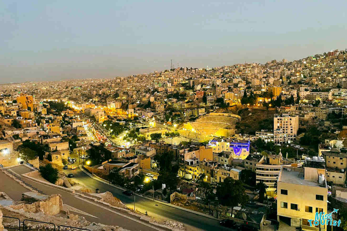 An evening view of Amman, showcasing the lit Roman Theater amid the glowing city lights