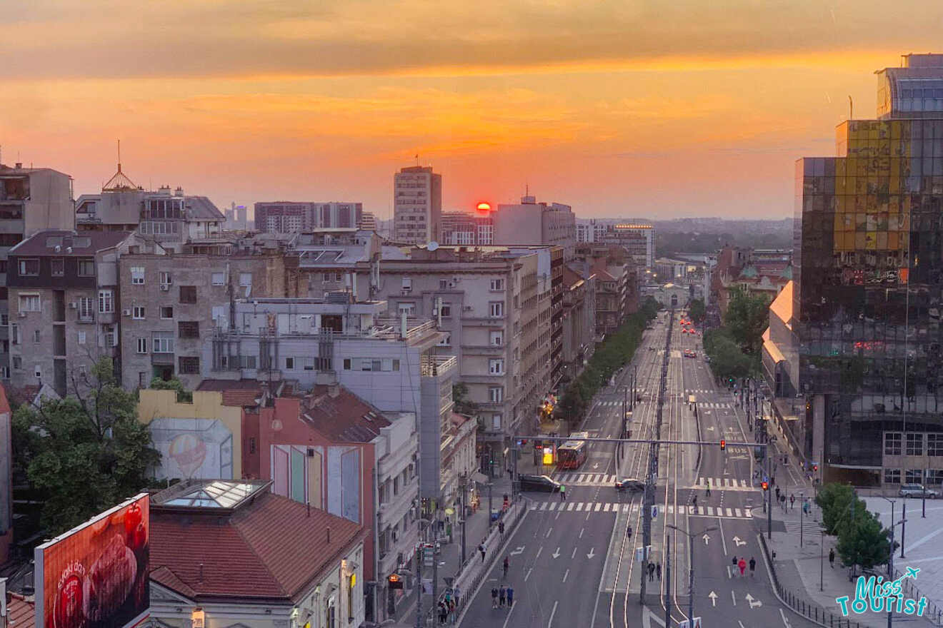 The cityscape of Belgrade during sunset, capturing the warm glow of the setting sun against the urban backdrop and busy streets