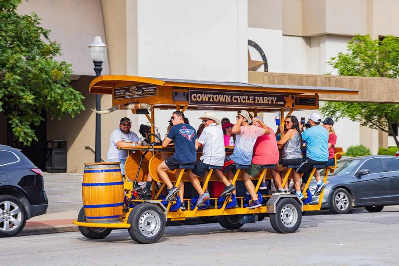 A group of people engaging in a social pedal tavern experience on a multi-person bike, highlighting a fun urban outdoor activity in Forth Worth.