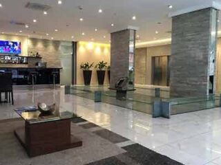 A sleek hotel lobby featuring polished floors, a large reception desk, and contemporary decor for a welcoming entrance.