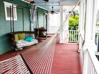 Quaint Isetta Inn porch with a relaxing hammock and seating area on a classic Southern home's veranda.