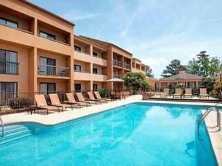 Courtyard by Marriott Savannah Midtown featuring a spacious outdoor pool with ample lounge chairs and a three-story hotel building.