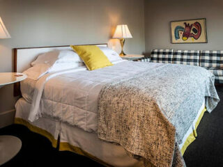 Charming bedroom in Hotel Broad Ripple with a checkered headboard, white and yellow bedding, and abstract art
