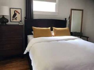 Bedroom in Vintage Getaway with a comfortable bed, wood headboard, and matching side tables, accented by yellow pillows and vintage decor.