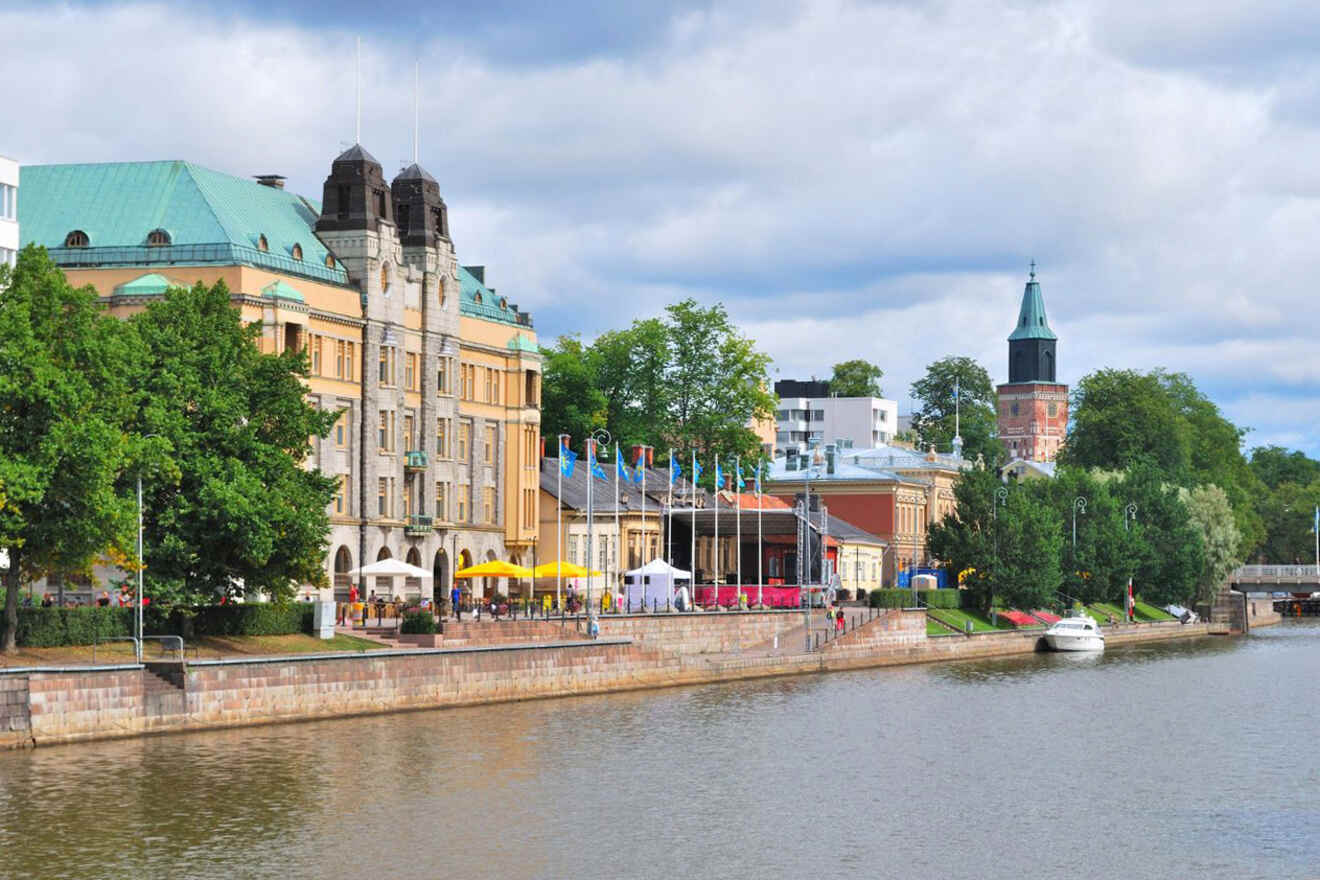 Scenic view of the Aura River in Turku, with riverside cafes and people strolling along the promenade on a sunny day