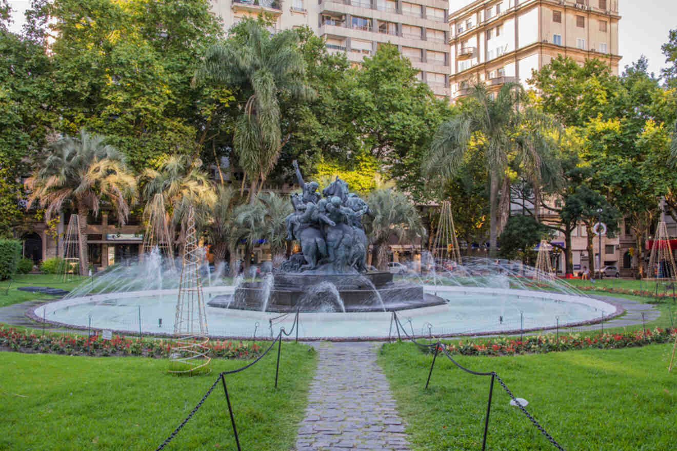 Tranquil urban park featuring a majestic fountain sculpture surrounded by sprays of water, with lush palm trees, well-kept grass, and a cobblestone path inviting a peaceful walk, nestled in the heart of the city.