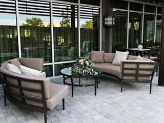 Outdoor seating area at Courtyard by Marriott Savannah Airport with cozy couches and a coffee table on a tiled patio.