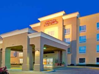 The exterior of a Hampton Inn & Suites hotel at twilight, showcasing its welcoming entrance and classic architectural design.