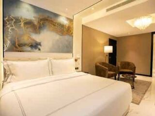 An elegant hotel bedroom with a large bed, an artistic mural of golden horses, and a plush seating area, offering a luxurious ambiance.
