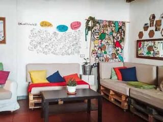 A vibrant hostel lounge with colorful sofas, eclectic wall art, and a playful comic-strip mural, creating a lively and social atmosphere.