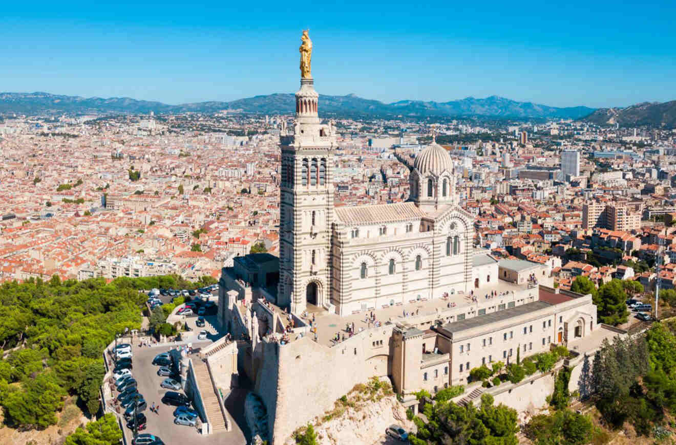 The Basilica of Notre-Dame de la Garde in Marseille, France, standing atop a hill with panoramic views of the city and hills in the distance