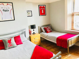 A Liverpool-themed guest room with a double bed and a single bed, both adorned with football decor