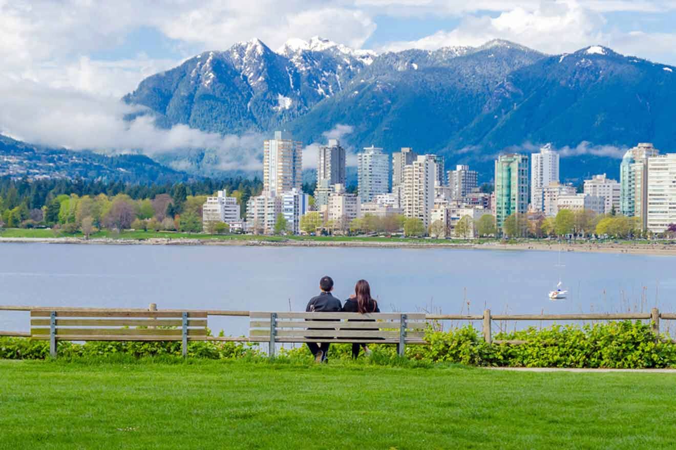 A couple sitting on a park bench overlooking the Vancouver skyline with snow-capped mountains in the background