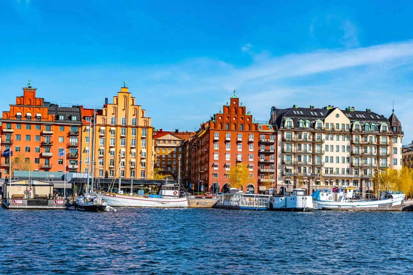 Colorful waterfront architecture of Kungsholmen in Stockholm, with vividly painted buildings in shades of orange and yellow, boats moored along the quay, under a clear blue sky