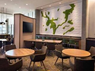 A hotel lounge area with a unique green map of the world wall art, modern furniture, and a relaxed, welcoming atmosphere for guests.