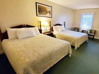 A twin bedroom with two large beds, patterned bedspreads, and simple decor, offering a clean and functional space for multiple guests.