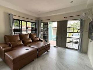 Spacious living room with a large brown leather sectional sofa and ample natural light from windows, offering a comfortable and relaxing indoor retreat.