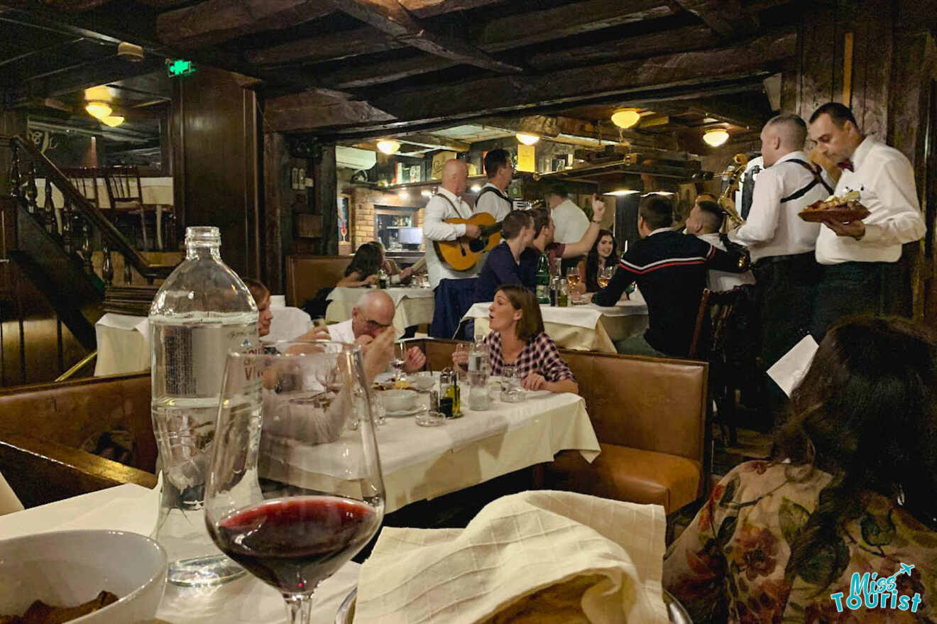 A lively traditional restaurant with people dining, musicians playing, and a vibrant atmosphere captured in Belgrade's nightlife scene