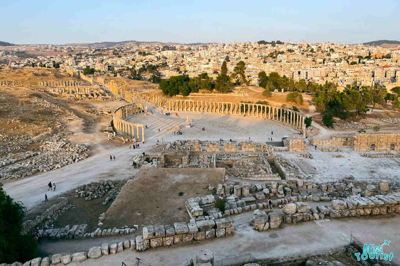An aerial view of the ancient Roman ruins in Jerash near Amman, Jordan, during golden hour, with visitors exploring the vast archaeological site