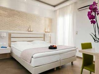 Comfortable and stylish bedroom with a large bed, white brick feature wall, and a vibrant orchid.