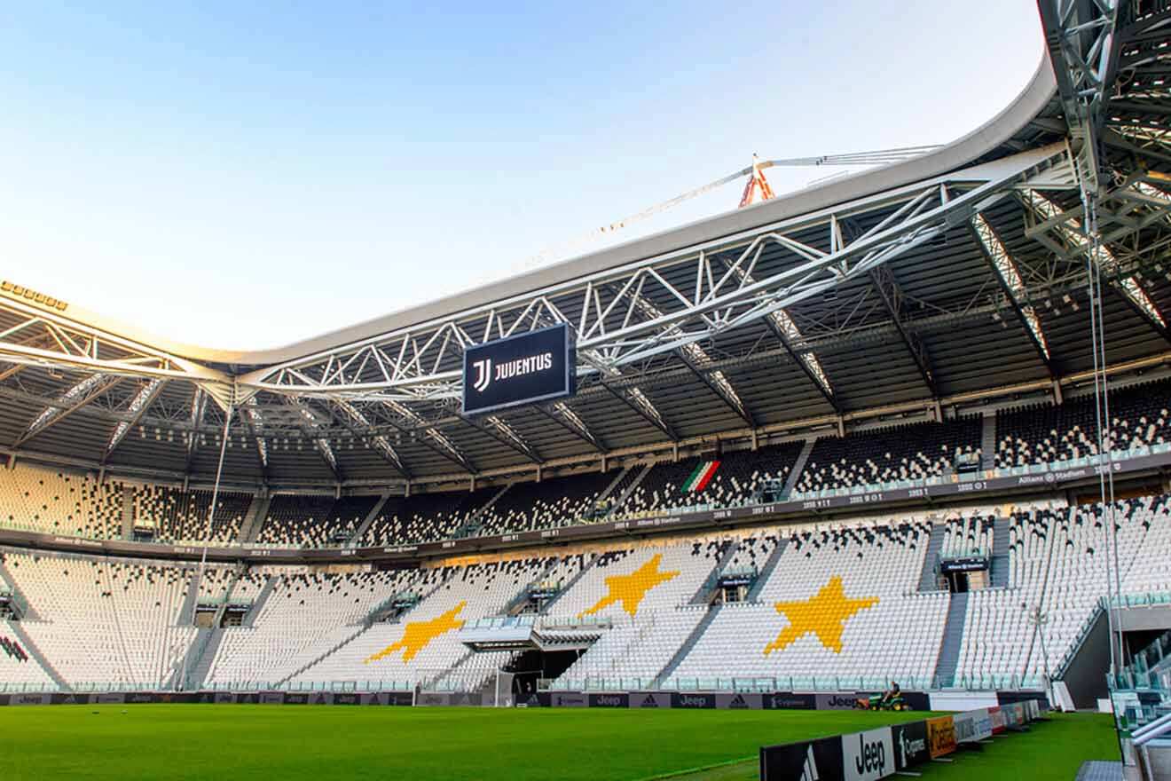 The iconic Allianz Stadium in Turin, home of Juventus Football Club, captured in daylight showcasing the empty stands with the club's black and white colors and distinctive star motifs.