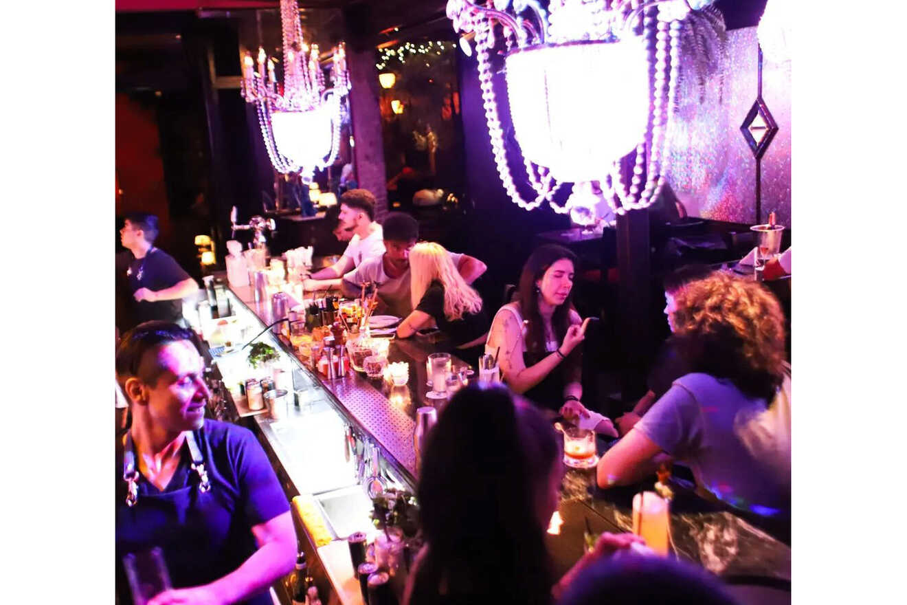 An eclectic and vibrant bar scene at Puerta Uno, with patrons engaged in conversation, illuminated by neon lights and chandeliers, creating a dynamic and lively atmosphere