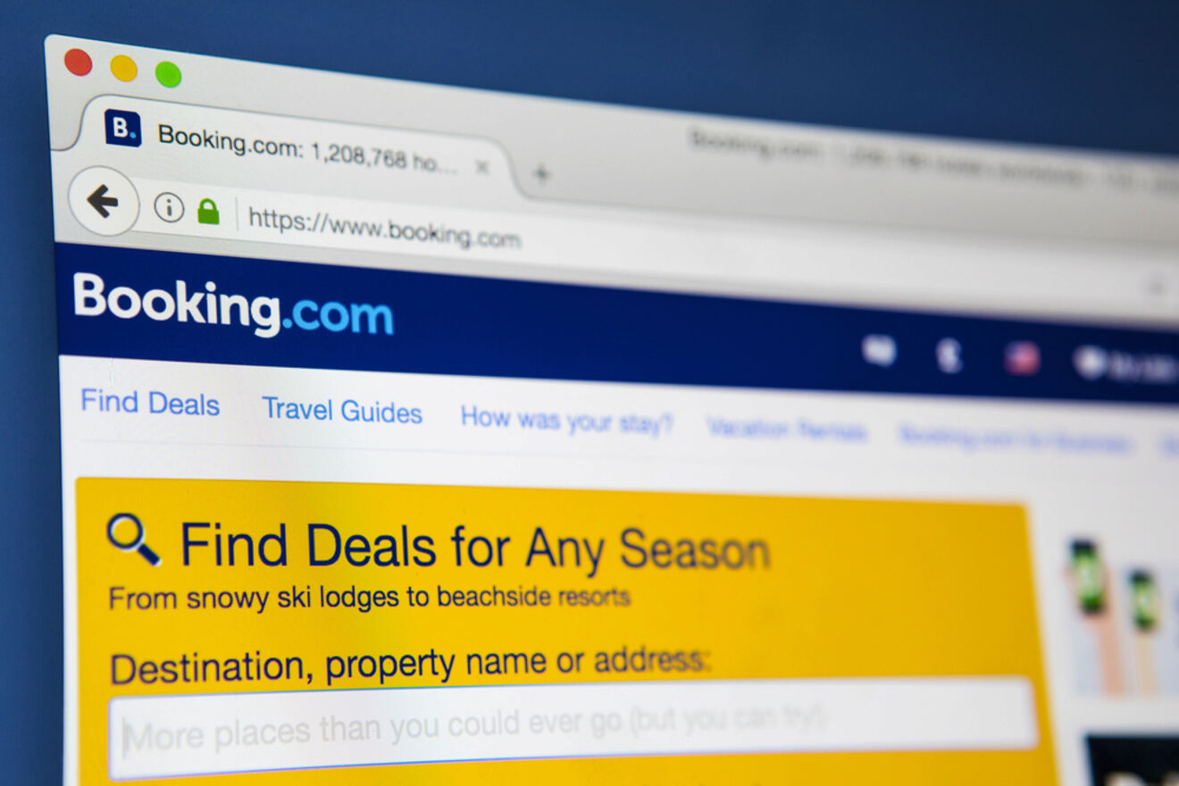 Close-up of a computer monitor displaying the Booking.com website with a prominent search bar under the header 'Find Deals for Any Season'. The blurred background suggests a focus on the website's deal-finding features for a variety of accommodations