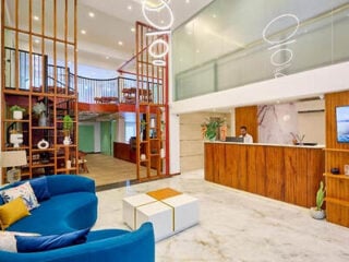Double-height lobby at Dutch Heritage Colombo, with a blue curved sofa, timber slat screen, spiral staircase and wooden reception desk.