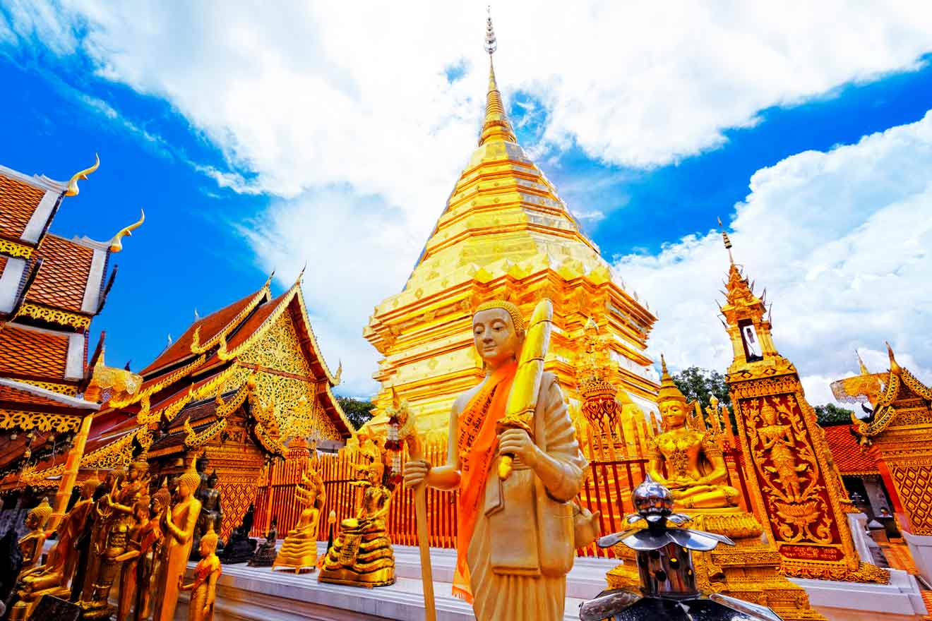 Statue of a standing monk draped in orange cloth in front of the golden stupa at Wat Phra That Doi Suthep, a popular accommodation area in Chiang Mai.