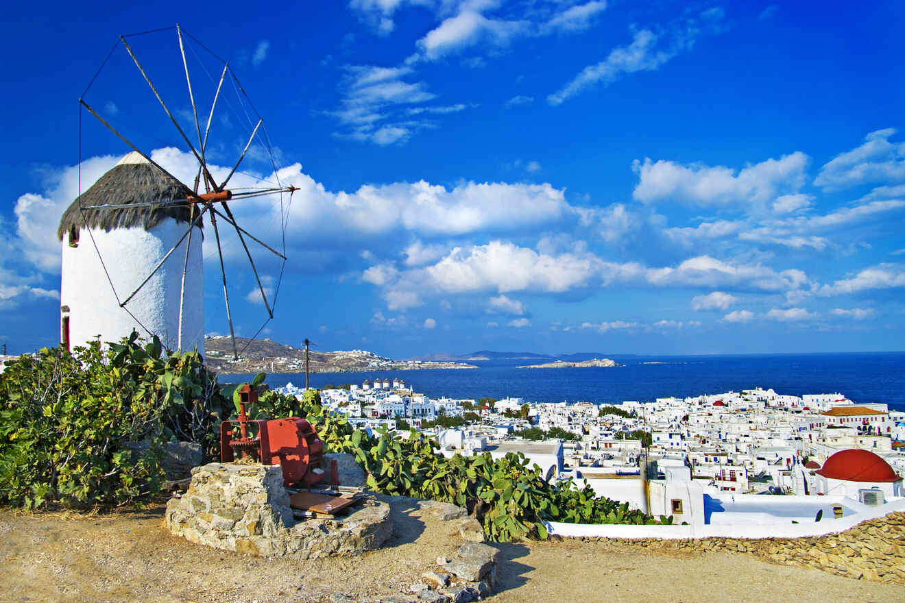 Traditional Greek windmill in Mykonos against a clear blue sky, with a panoramic view of the island's white buildings.



