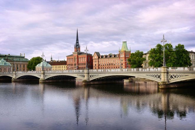 Tranquil scene of a bridge and waterways in Stockholm with buildings and greenery
