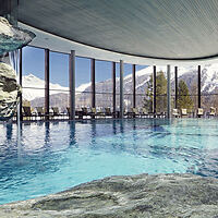 Indoor pool with panoramic mountain views through floor-to-ceiling windows.
