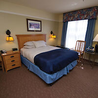 Comfortable and inviting hotel room with a neatly made bed, two bedside lamps, and a wooden writing desk