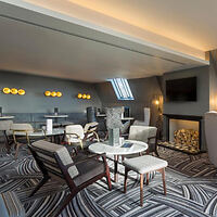 Elegant hotel lounge with plush seating, striking black-and-white carpet design, and ambient lighting from unique fixtures