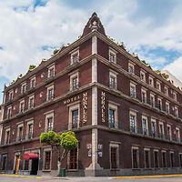 The historic Hotel Morales in Guadalajara, showcasing its classic red brick facade with green trimmed windows and a triangular pediment