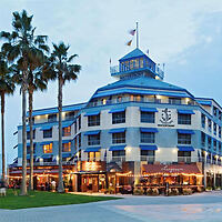 Iconic Waterfront Hotel with blue facade, palm trees, and outdoor dining