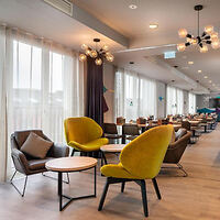 Bright and stylish hotel lounge at The Niu Charly, featuring contemporary furniture with vibrant yellow chairs and artistic lighting